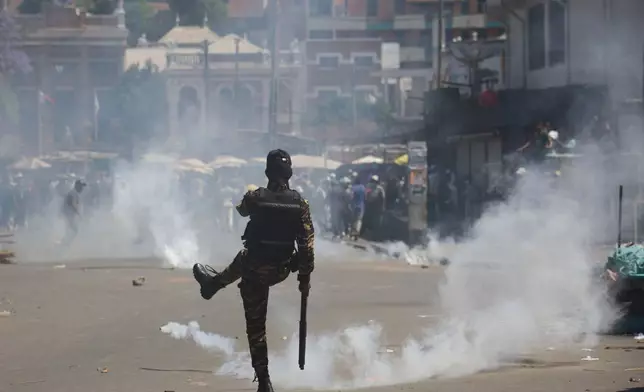 A police officer kicks back a teargas canister during a protest calling for the president to step down in Antananarivo, Madagascar, Thursday, Oct. 9, 2025. (AP Photo/Alexander Joe)