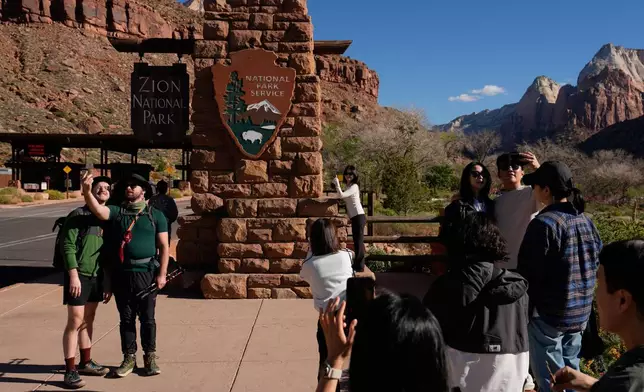 People stand near an entrance to Zion National Park, Wednesday, Oct. 1, 2025, in Springdale, Utah. (AP Photo/John Locher)