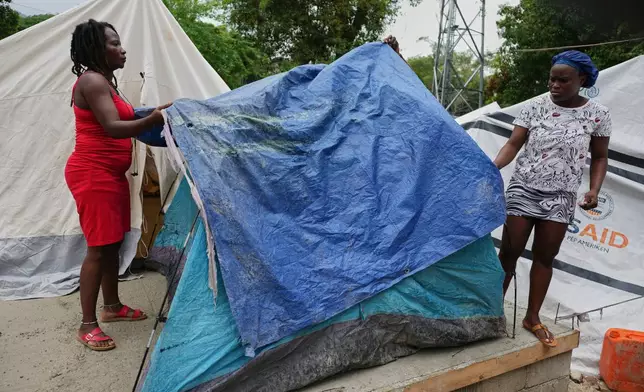People place plastic tarps over their tents ahead of expected rain at a shelter for families displaced by gang violence in Port-au-Prince, Haiti, Thursday, Oct. 23, 2025. (AP Photo/Odelyn Joseph)