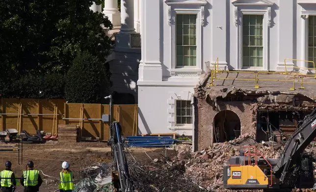 Construction workers atop the U.S. Treasury, bottom left, watch as work continues on a largely demolished part of the East Wing of the White House, Thursday, Oct. 23, 2025, in Washington, before construction of a new ballroom. (AP Photo/Jacquelyn Martin)