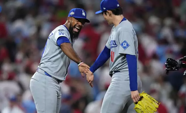 Los Angeles Dodgers' Teoscar Hernández, left, and Roki Sasaki celebrate after the Dodgers won Game 1 of baseball's National League Division Series against the Philadelphia Phillies, Saturday, Oct. 4, 2025, in Philadelphia. (AP Photo/Matt Slocum)