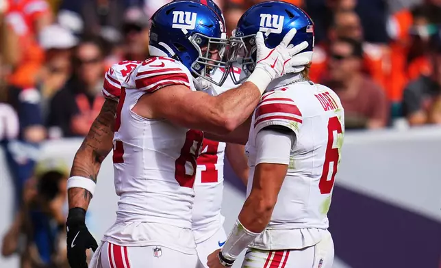 New York Giants tight end Daniel Bellinger, left, celebrates with quarterback Jaxson Dart (6) after connecting on a touchdown pass during the first half of an NFL football game against the Denver Broncos in Denver, Sunday, Oct. 19, 2025. (AP Photo/Jack Dempsey)
