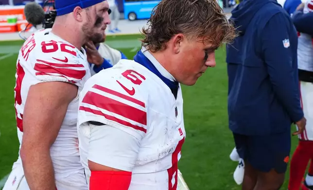 New York Giants tight end Daniel Bellinger, left, and quarterback Jaxson Dart walk off the field after an NFL football game against the Denver Broncos in Denver, Sunday, Oct. 19, 2025. (AP Photo/Jack Dempsey)