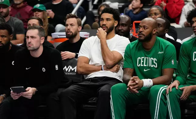 Boston Celtics forward Jayson Tatum, center, watches from the bench during the first half of an NBA basketball game against the Detroit Pistons, Sunday, Oct. 26, 2025, in Detroit. (AP Photo/Ryan Sun)
