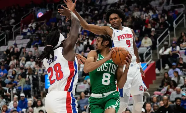 Boston Celtics forward Josh Minott, center, vies for the ball against Detroit Pistons forwards Isaiah Stewart, left, and Ausar Thompson, right, during the first half of an NBA basketball game Sunday, Oct. 26, 2025, in Detroit. (AP Photo/Ryan Sun)