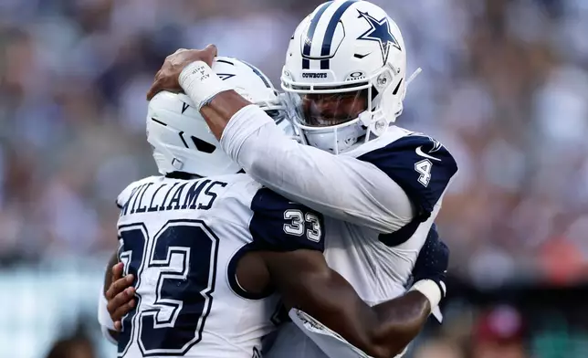 Dallas Cowboys' Dak Prescott hugs Javonte Williams after a touchdown during the second half of an NFL football game against the New York Jets Sunday, Oct. 5, 2025, in East Rutherford, N.J. (AP Photo/Adam Hunger)