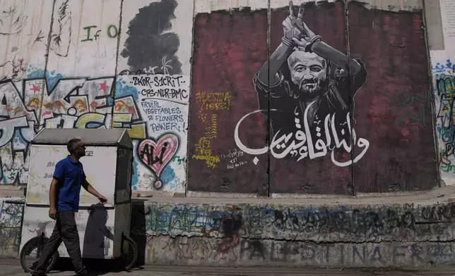 FILE - A man walks past a mural depicting the Palestinian leader Marwan Barghouti, with a message that reads in Arabic, "See you soon,” on Israel's separation barrier in the West Bank city of Bethlehem, Aug. 20, 2025. (AP Photo/Mahmoud Illean, File)