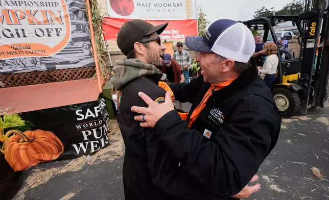Brandon Dawson, left, is congratulated by Travis Gienger, who was last year's champion, after winning the Safeway 52nd annual World Championship Pumpkin Weigh-Off in Half Moon Bay, Calif., Monday, Oct. 13, 2025. (AP Photo/Godofredo A. Vásquez)