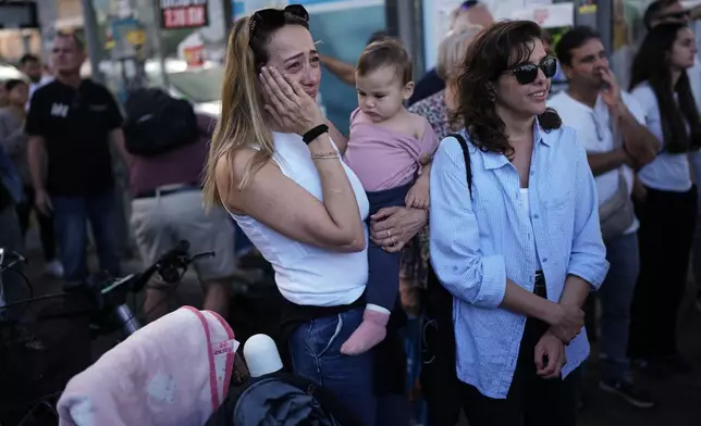 People react as they gather to watch a live broadcast of Israeli hostages released from Gaza at a plaza known as hostages square in Tel Aviv, Israel, Monday, Oct. 13, 2025. The release took place as part of a cease-fire agreement between Israel and Hamas. (AP Photo/Oded Balilty)