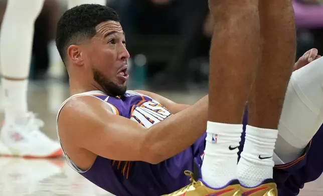 Phoenix Suns guard Devin Booker reacts after getting hit in the face during the first half of an NBA basketball game against the Sacramento Kings, Wednesday, Oct. 22, 2025, in Phoenix. (AP Photo/Rick Scuteri)