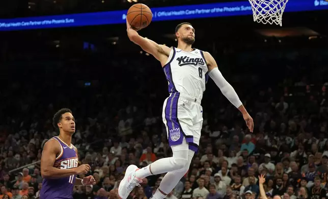 Sacramento Kings guard Zach LaVine (8) dunks over Phoenix Suns forward Oso Ighodaro during the first half of an NBA basketball game, Wednesday, Oct. 22, 2025, in Phoenix. (AP Photo/Rick Scuteri)