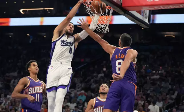 Sacramento Kings guard Zach LaVine (8) dunks over Phoenix Suns forward Oso Ighodaro (11), guard Devin Booker, and guard Grayson Allen (8) during the first half of an NBA basketball game, Wednesday, Oct. 22, 2025, in Phoenix. (AP Photo/Rick Scuteri)