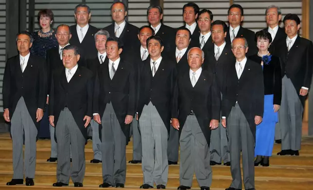 FILE - Newly-appointed Japanese Prime Minister Shinzo Abe, front row third from right, poses with his Cabinet members after an attestation ceremony for his Cabinet at the Imperial Palace in Tokyo, on Sept. 26, 2006. Front row from left: Education, Culture, Sports, Science and Technology Minister Bunmei Ibuki, Environment Minister Masatoshi Wakabayashi, Foreign Minister Taro Aso, Abe, Defense Agency Director General Fumio Kyuma and Finance Minister Koji Omi. Second row from left: Justice Minister Jinen Nagase, Health, Labor and Welfare Minister Hakuo Yanagisawa, Internal Affairs and Communications Minister Yoshihide Suga, Land, Infrastructure and Transport Minister Tetsuzo Fuyushiba and Economy, Trade and Industry Ministry Akira Amari and Economy and Banking Minister Hiroko Ota. Third row from left: Okinawa and Northern Territories, Innovation, Gender Equality and Food Safety Minister Sanae Takaichi, National Public Safety Commission Chairman Kensei Mizote, Administrative Reforms Minister Genichiro Sata, unidentified, unidentified, Toshikatsu Matsuoka, Yuji Yamamoto, unidentified and Chief Cabinet Secretary, also in charge of resolving North Korea's abductions of Japanese citizens Yasuhisa Shiozaki. (AP Photo/Itsuo Inouye, File)