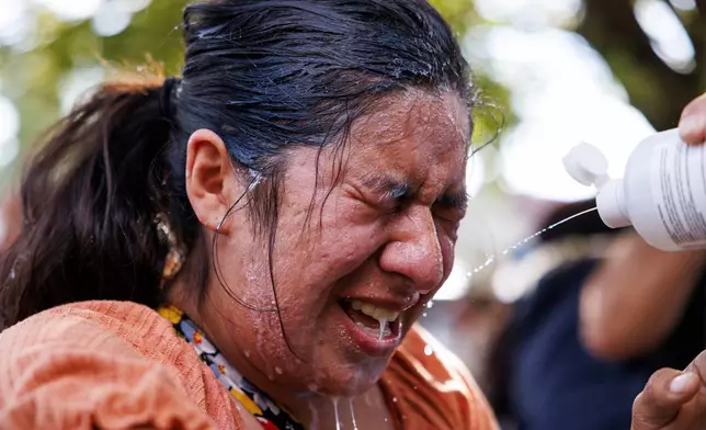 A protester is doused with milk, water, and saline after tear gas in the Brighton Park neighborhood of Chicago, on Saturday, Oct. 4, 2025, after protesters learned that U.S. Border Patrol shot a woman Saturday morning on Chicago's Southwest Side. (Anthony Vazquez/Chicago Sun-Times via AP)