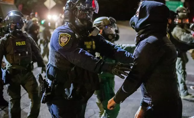 Protesters confront federal law enforcement officers outside a U.S. Immigration and Customs Enforcement facility in Portland, Ore., Monday, Oct. 6, 2025. (AP Photo/Ethan Swope)