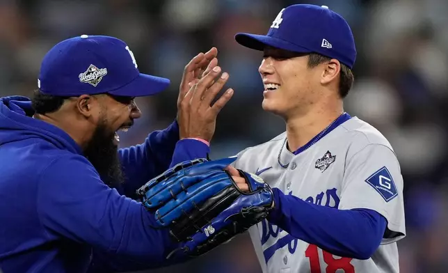 Los Angeles Dodgers pitcher Yoshinobu Yamamoto celebrates with right fielder Teoscar Hernández after throwing compete game against the Toronto Blue Jays in Game 2 of baseball's World Series, Saturday, Oct. 25, 2025, in Toronto. (AP Photo/Brynn Anderson)