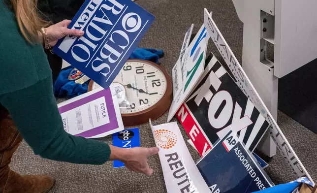 Washington Post reporter Tara Copp saves the name plaques from various news organizations as she and members of the media pack up their belongings in the press area in the Pentagon, Wednesday, Oct. 15, 2025 in Washington. (AP Photo/Kevin Wolf)