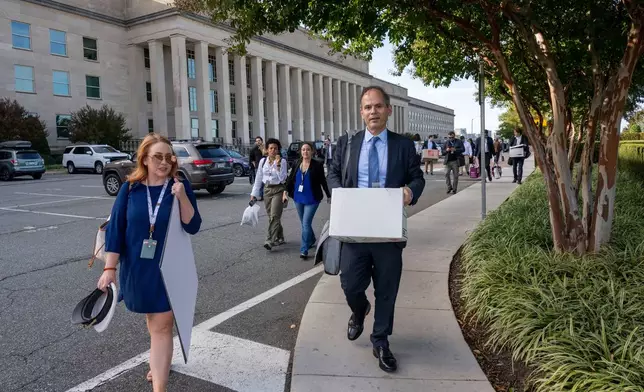 Members of the Pentagon press corp carry their belongings out of the Pentagon after turning in their press credentials, Wednesday, Oct. 15, 2025 in Washington. (AP Photo/Kevin Wolf)