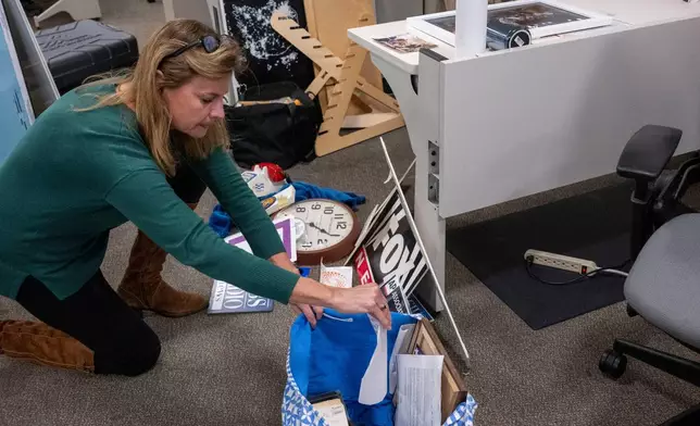 Washington Post reporter Tara Copp saves the name plaques from various news organizations as she and members of the media pack up their belongings in the press area in the Pentagon, Wednesday, Oct. 15, 2025 in Washington. (AP Photo/Kevin Wolf)