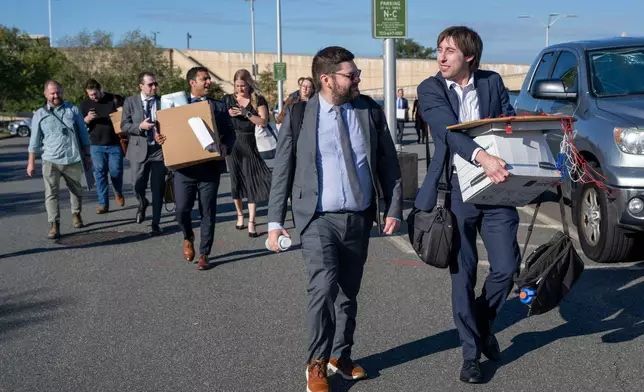Members of the Pentagon press corp carry their belongings out of the Pentagon after turning in their press credentials, Wednesday, Oct. 15, 2025 in Washington. (AP Photo/Kevin Wolf)