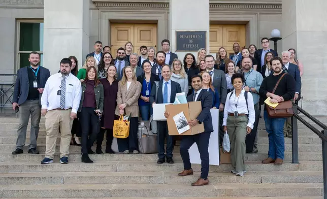 Members of the Pentagon press corp gather for a group photo after turning in their press credentials, Wednesday, Oct. 15, 2025 in Washington. (AP Photo/Kevin Wolf)