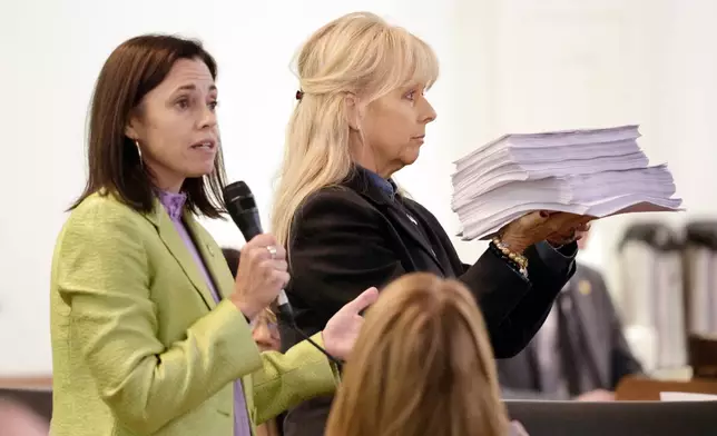 Rep. Beth Helfrich, D-Mecklenberg, left, refers to a stack of public comments held by Rep. Julia Greenfield, D-Mecklenberg, right, during debate on a redistricting bill at the Legislative Building, Wednesday, Oct. 22, 2025, in Raleigh, N.C. (AP Photo/Chris Seward)