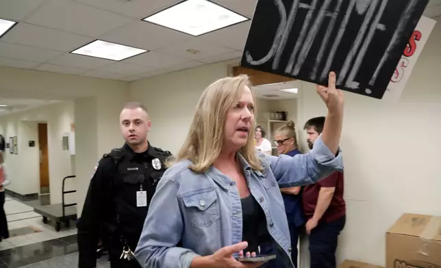 A protester opposed to the proposed redistricting map is escort out by law enforcement during a House Redistricting Committee meeting Tuesday, Oct. 21, 2025, in Raleigh, N.C. (AP Photo/Chris Seward)