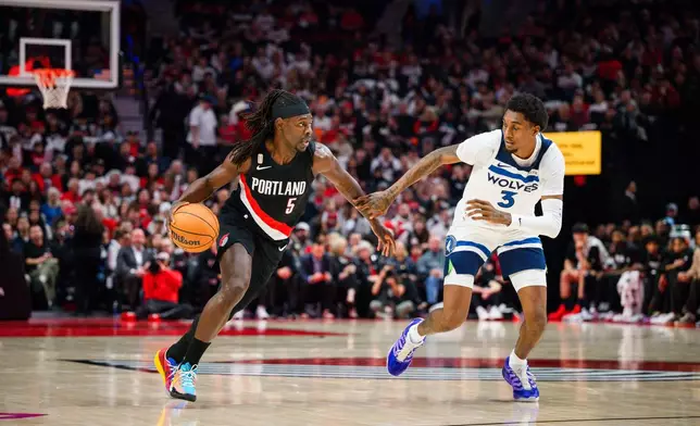 Portland Trail Blazers guard Jrue Holiday (5) drives down the court past Minnesota Timberwolves forward Jaden McDaniels (3) during the first half of an NBA basketball game on Wednesday, Oct. 22, 2025, in Portland, Ore. (AP Photo/Molly J. Smith)