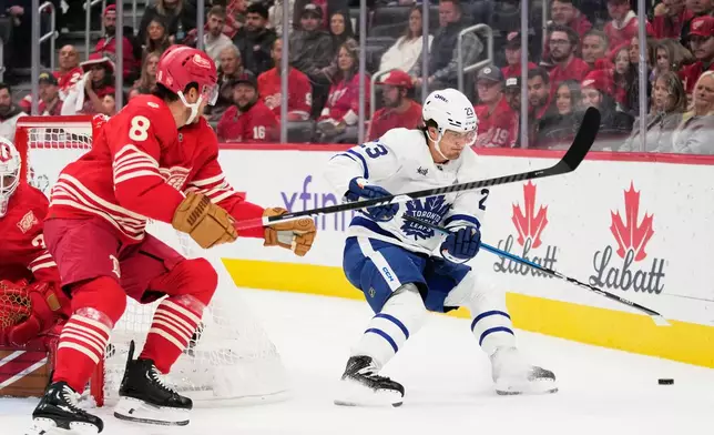 Toronto Maple Leafs left wing Matthew Knies, right, and Detroit Red Wings defenseman Ben Chiarot (8) chase the puck during the first period of an NHL hockey game, Saturday, Oct. 11, 2025, in Detroit. (AP Photo/Ryan Sun)
