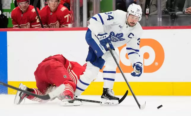 Toronto Maple Leafs center Auston Matthews, right, vies for the puck against Detroit Red Wings defenseman Simon Edvinsson during the first period of an NHL hockey game Saturday, Oct. 11, 2025, in Detroit. (AP Photo/Ryan Sun)