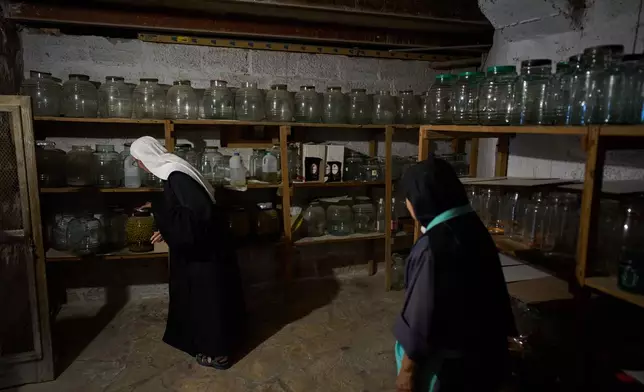 Sister Marie Benedicte, left, and Sister Colomba, two Catholic nuns, check on the olive preserves that were made in past years from the harvest in their monastery's garden on the Mount of Olives, in Jerusalem, Friday, Oct. 17, 2025. (AP Photo/Oded Balilty)