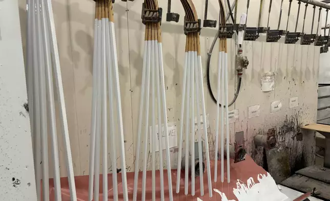 Wooden hockey sticks are stacked as they move along the assembly line at the Roustan Hockey factory, which is the last major manufacturer of hockey sticks in Canada on Aug. 27, 2025 in Brantford, Ontario. (AP Photo/Kelvin Chan)