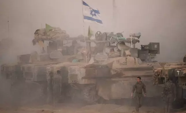 Israeli soldiers stand near their tanks along the Israeli-Gaza border, as seen from southern Israel, Friday, Oct. 10, 2025, after Israel and Hamas have agreed to a pause in their war and the release of the remaining hostages. (AP Photo/Emilio Morenatti)