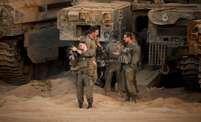 Israeli soldiers stand near their tanks along the Israeli-Gaza border, as seen from southern Israel, Friday, Oct. 10, 2025, after Israel and Hamas have agreed to a pause in their war and the release of the remaining hostages. (AP Photo/Emilio Morenatti)