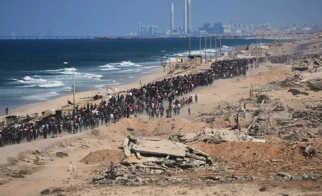 Displaced Palestinians walk along the coastal road near Wadi Gaza in the central Gaza Strip, moving toward northern Gaza, Friday, Oct. 10, 2025, after Israel and Hamas have agreed to a pause in their war and the release of the remaining hostages. (AP Photo/Abdel Kareem Hana)