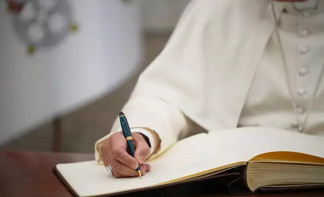 Pope Leo XIV signs the FAO Golden Book register of honor as he attends a ceremony marking the 80th anniversary of World Food Day at the FAO headquarters in Rome, Thursday, Oct. 16, 2025. (AP Photo/Alessandra Tarantino)