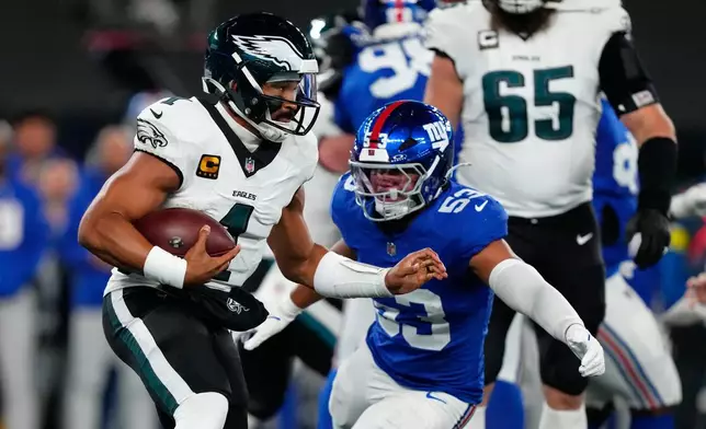 Philadelphia Eagles' Jalen Hurts, left, tries to get [past New York Giants' Darius Muasau during the first half of an NFL football game Thursday, Oct. 9, 2025, in East Rutherford, N.J. (AP Photo/Yuki Iwamura)