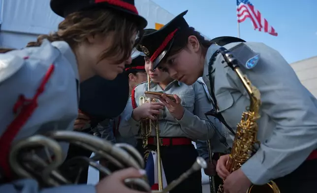 Members of an Israeli military band listen to a live broadcast showing the first group of hostages being released from Hamas captivity in Gaza, ahead of a welcoming ceremony for U.S. President Donald Trump's arrival at Ben Gurion Airport near Tel Aviv, Israel, Monday, Oct. 13, 2025. (AP Photo/Ariel Schalit)