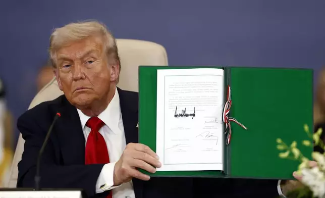 President Donald Trump shows a signed document during the signature ceremony at the Gaza International Peace Summit, in Sharm el-Sheikh, Egypt, Monday, Oct.13 2025. (Yoan Valat, Pool photo via AP)