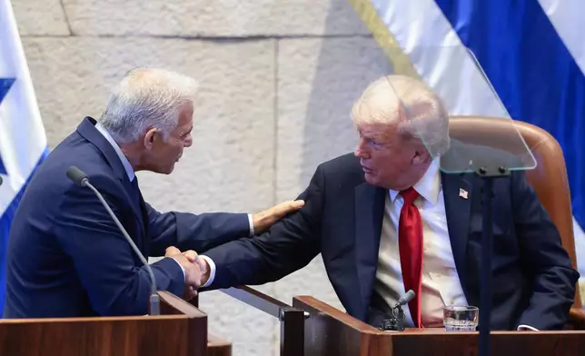 President Donald Trump shakes hands with Israeli opposition leader Yair Lapid at the Knesset, Israel's parliament, Monday, Oct. 13, 2025, in Jerusalem. (Evelyn Hockstein/Pool via AP)