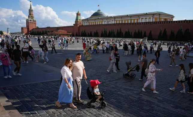 FILE - A family walks through Red Square in Moscow, Russia, Sunday, Aug. 4, 2024. (AP Photo/Alexander Zemlianichenko, File)