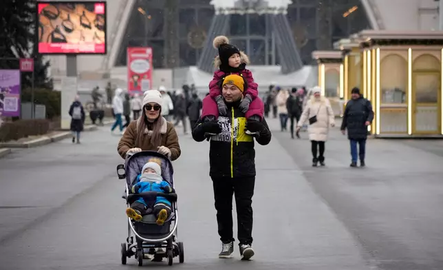 FILE - A couple and their children walk through the Exhibition of the Achievements of the People's Economy in Moscow, Russia, Thursday, Feb. 13, 2025. (AP Photo/Alexander Zemlianichenko, File)