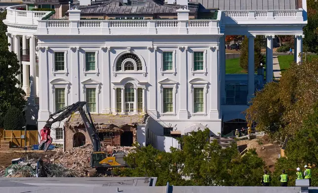 Construction workers, bottom right, atop the U.S. Treasury, watch watch as demolition continues on the East Wing of the White House to make room for a new ballroom, in Washington, Oct. 22, 2025. (AP Photo/Jacquelyn Martin)