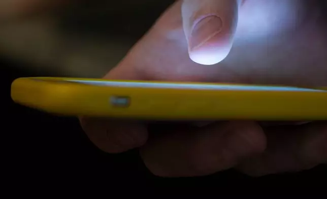 FILE - A man uses a cell phone in New Orleans, Aug. 11, 2019. (AP Photo/Jenny Kane, File)