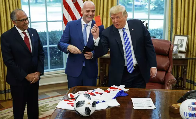 FILE - President Donald Trump holds up a red card during a meeting with FIFA president Gianni Infantino, center, and United States Soccer Federation president Carlos Cordeiro, left, in the Oval Office of the White House, Aug. 28, 2018, in Washington. (AP Photo/Evan Vucci, File)