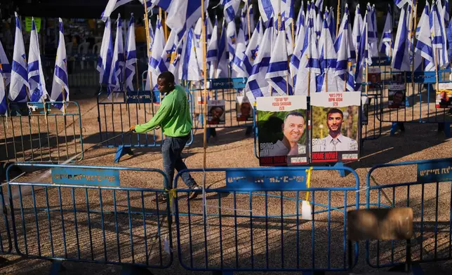 A worker cleans the ground at the plaza known as hostages square, in Tel Aviv, Israel, Tuesday, Oct. 14, 2025. (AP Photo/Francisco Seco)