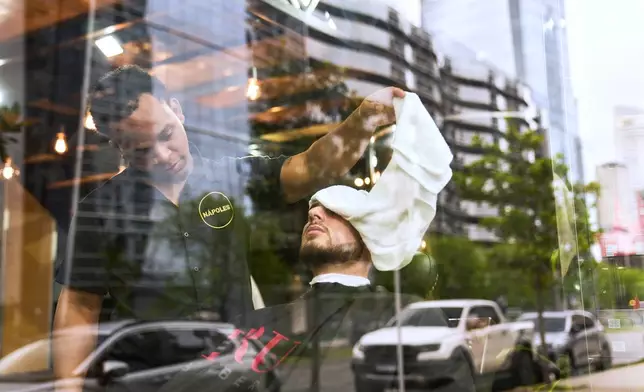 A barber tends to a customer at a barbershop in the Puerto Madero neighborhood of Buenos Aires, Argentina, Friday, Oct. 24, 2025. (AP Photo/Rodrigo Abd)