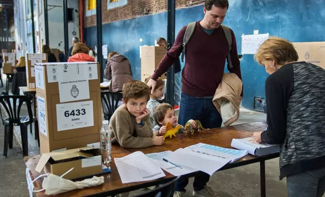 Patricio Irarrazabal arrives to vote with his sons during legislative midterm elections in Buenos Aires, Argentina, Sunday, Oct. 26, 2025. (AP Photo/Rodrigo Abd)
