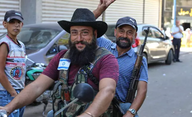 Two Druze gunmen pose for a photo while riding a motorcycle, one wearing a vest with an Israeli flag patch, in Sweida, southern Syria, on Sept. 18, 2025. (AP Photo/Fahd Kiwan)