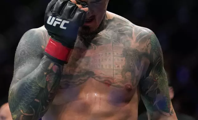 England's Tom Aspinall compresses his right eye leaves after it was poked by Ciryl Gane of France during the heavyweight title bout at the UFC mixed martial arts Fight Night in Abu Dhabi, United Arab Emirates, Saturday, Oct. 25, 2025. (AP Photo/Altaf Qadri)